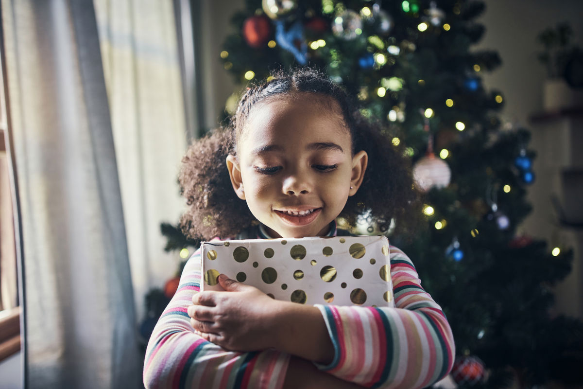 Meisje met kadootje bij kerstboom