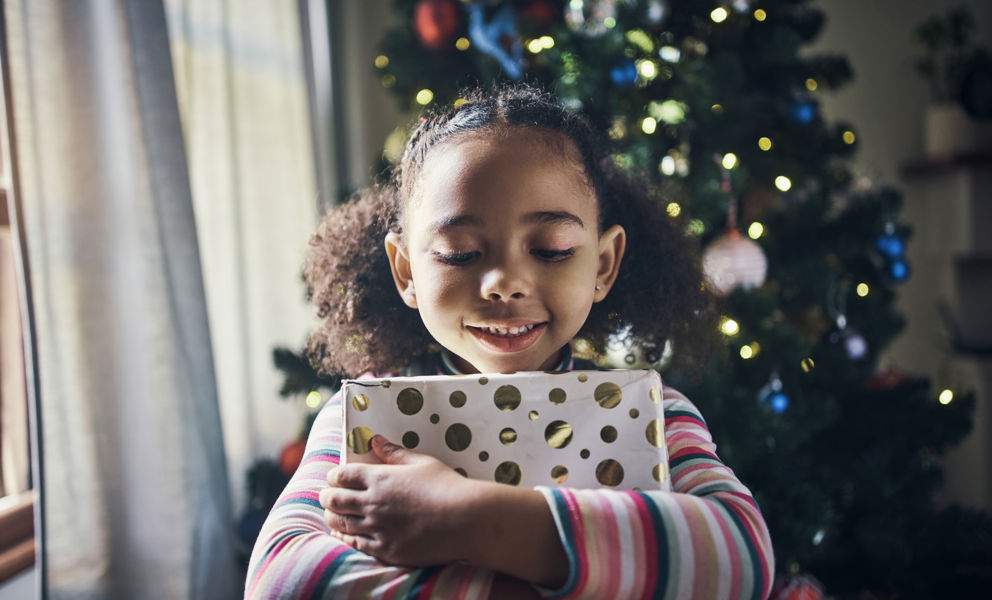 Meisje met kadootje bij kerstboom